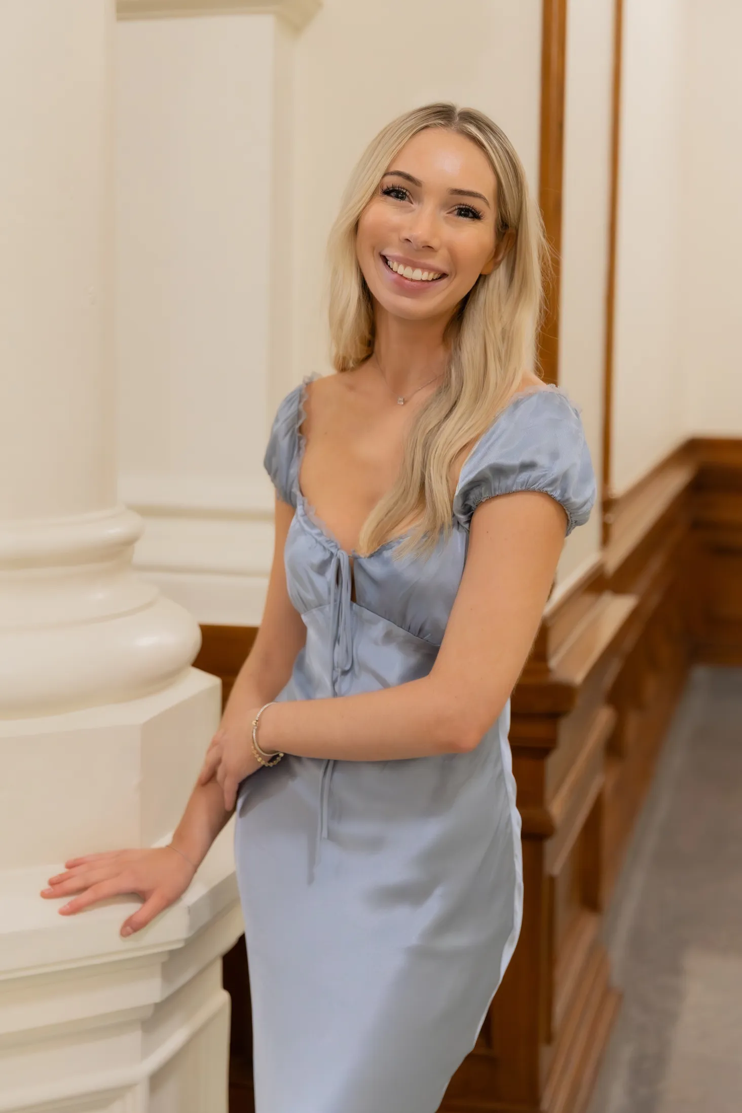 Daisy Flores of VinoCadre, smiling beside a white column.